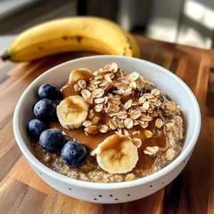 Bowl of decadent peanut butter oatmeal topped with fruit and nuts