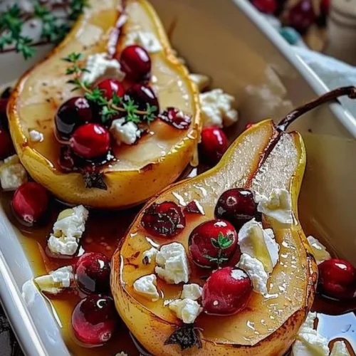 Baked pears with feta cheese, honey drizzle, and cranberries on a serving plate.