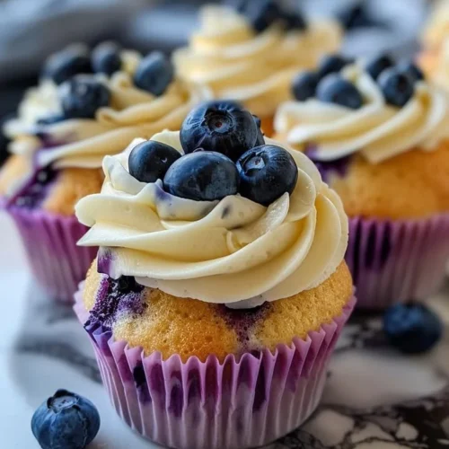 Delicious blueberry cupcakes with white chocolate frosting on a decorative platter.