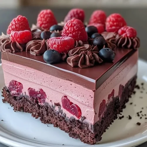 Delicious Chocolate Raspberry Mousse Cake topped with fresh raspberries and chocolate shavings.
