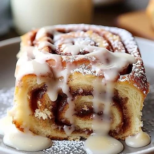 Delicious slice of Cinnamon Roll Poke Cake topped with icing and cinnamon.
