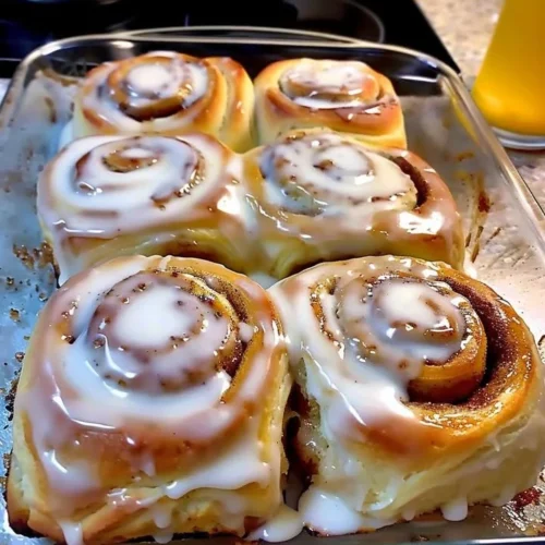 Delicious classic cinnamon rolls topped with icing on a plate