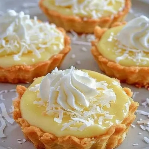 Delicious coconut cream tarts topped with whipped cream and toasted coconut