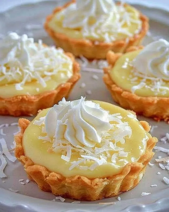 Delicious coconut cream tarts topped with whipped cream and toasted coconut