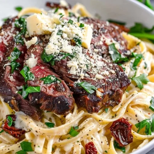 Delicious plate of Steak Gorgonzola Alfredo topped with creamy sauce and garnish.