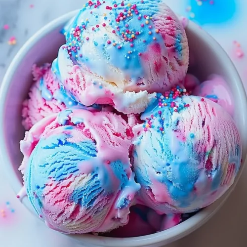 Delicious cotton candy ice cream served in a cone, topped with sprinkles.