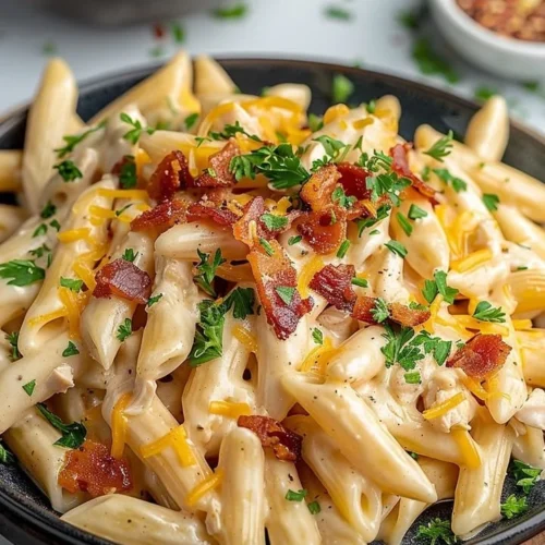 Plate of creamy Crack Chicken Penne pasta garnished with herbs.