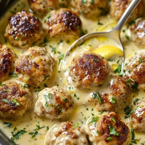 Creamy lemon pepper chicken meatballs served on a plate with herbs.