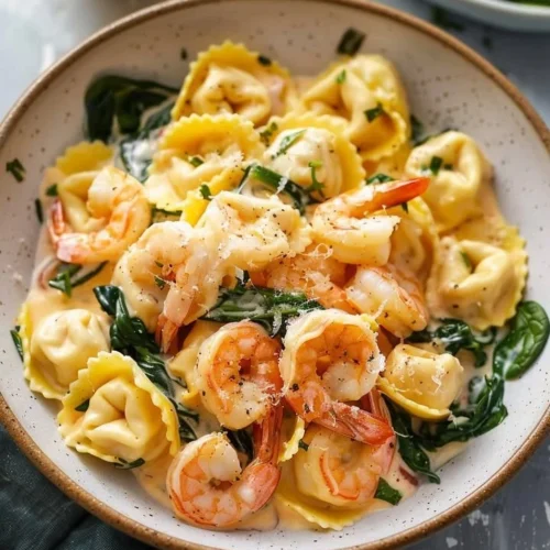 Creamy lemon shrimp tortellini served with fresh herbs and lemon slices.