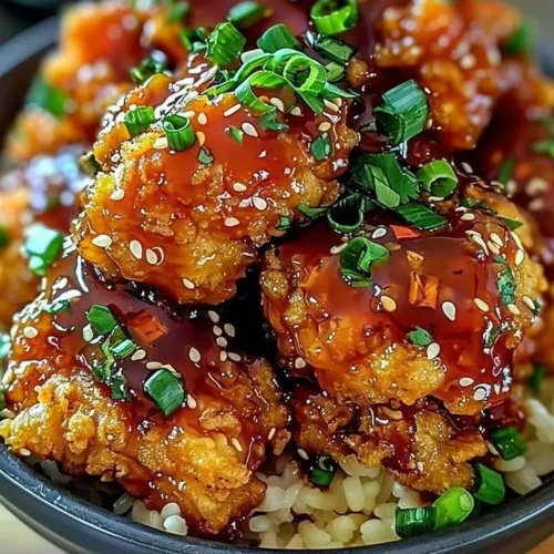 Crispy Bang Bang Chicken served with a spicy sauce and garnished with scallions.