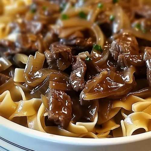 Delicious bowl of French Onion Beef and Noodles garnished with herbs