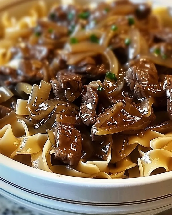 Delicious bowl of French Onion Beef and Noodles garnished with herbs