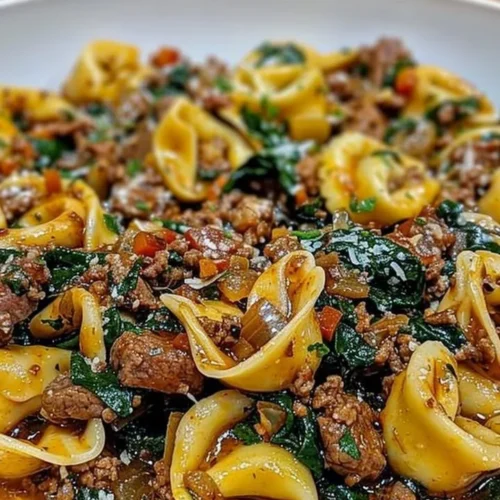 Delicious garlic butter beef with spinach tortellini dish garnished with herbs