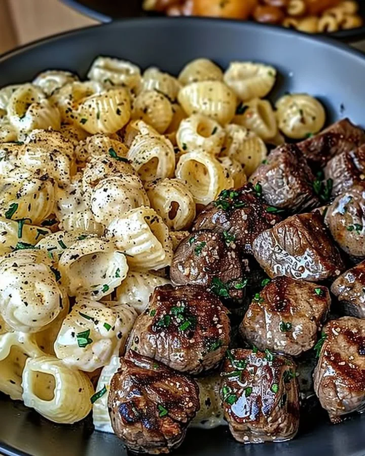 Garlic butter steak bites served with creamy Parmesan pasta shells on a plate