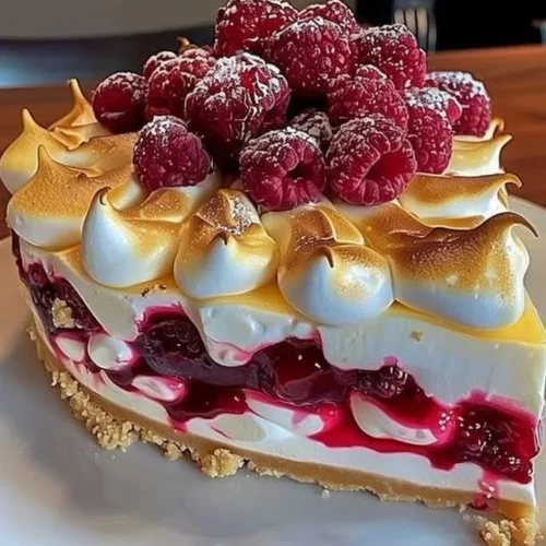 Heavenly Lemon Raspberry Meringue Cheesecake topped with fresh raspberries and meringue.
