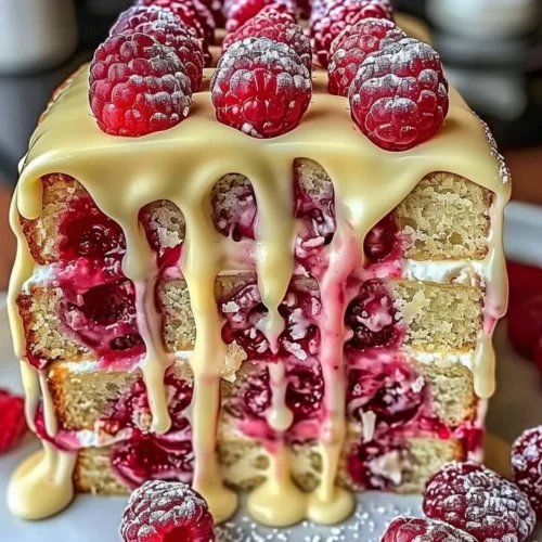 Heavenly White Chocolate Raspberry Cake topped with fresh raspberries and white chocolate shavings.