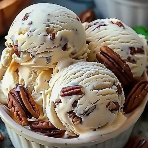 Bowl of homemade butter pecan ice cream with nuts and a spoon