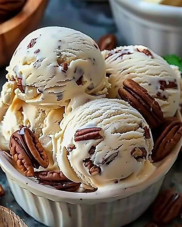 Bowl of homemade butter pecan ice cream with nuts and a spoon