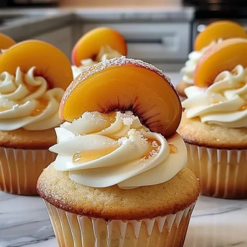 Honey Peach Cream Cheese Cupcakes topped with creamy frosting and fresh peaches.