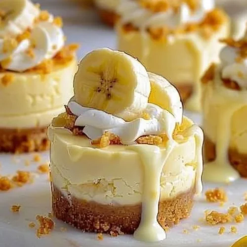Mini banana pudding cheesecakes topped with whipped cream and banana slices