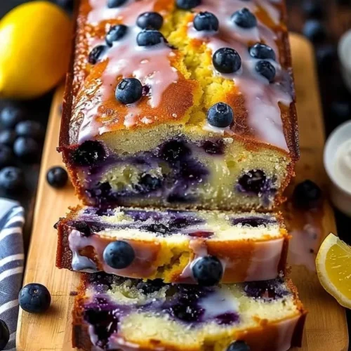 Slice of Lemon Blueberry Yogurt Loaf on a plate, showcasing blueberries and lemon zest