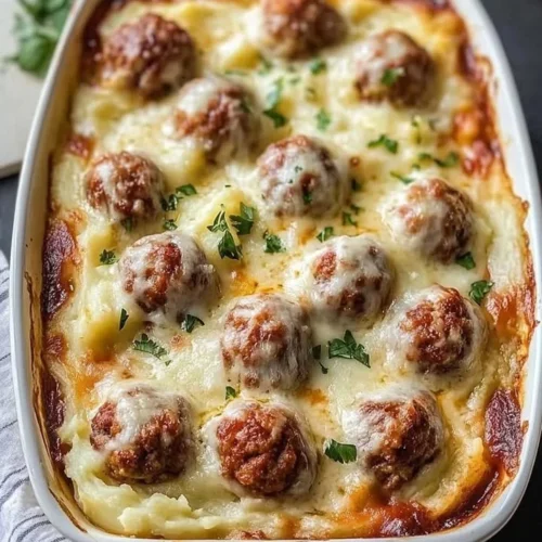 Loaded Mashed Potatoes and Meatballs Casserole topped with cheese and herbs