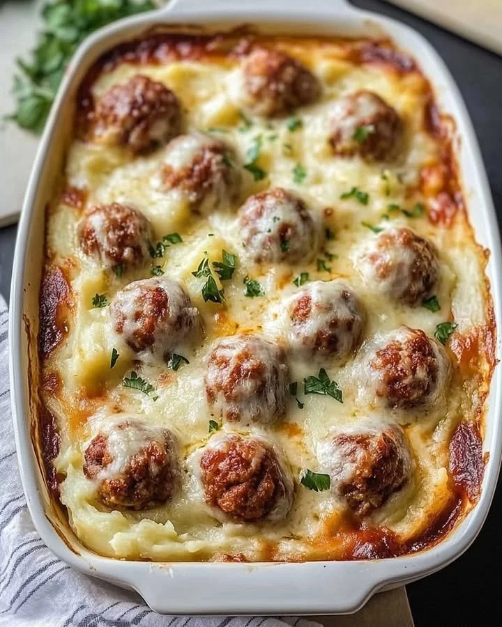 Loaded Mashed Potatoes and Meatballs Casserole topped with cheese and herbs