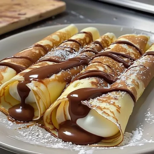 Nutella cream-filled crepes topped with chocolate sauce and strawberries
