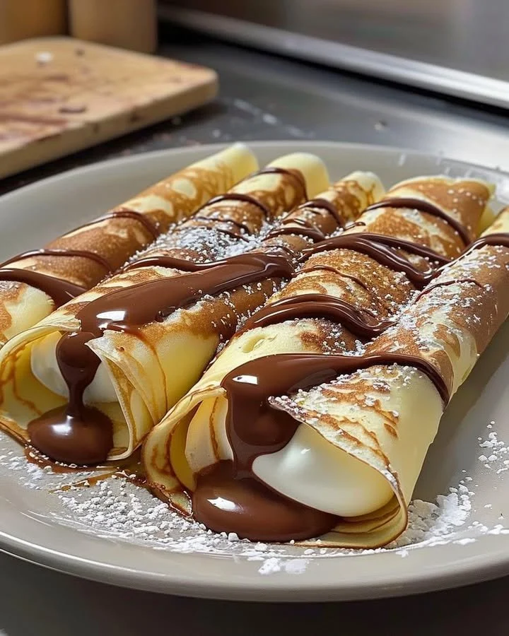 Nutella cream-filled crepes topped with chocolate sauce and strawberries