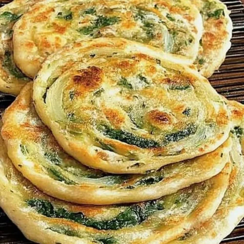 Pan-fried green onion and spinach flatbread on a plate.