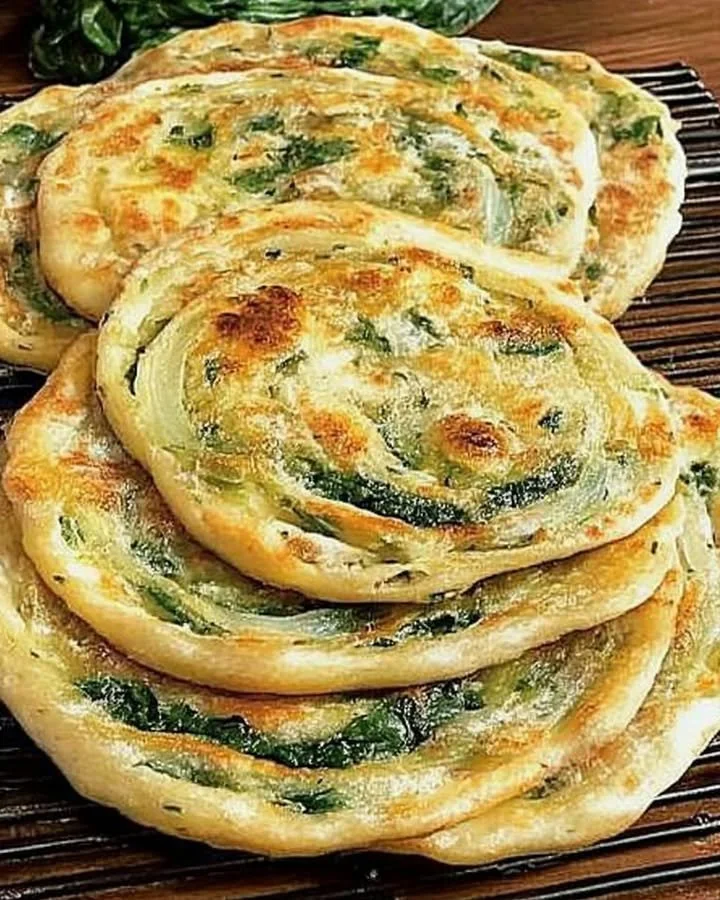Pan-fried green onion and spinach flatbread on a plate.