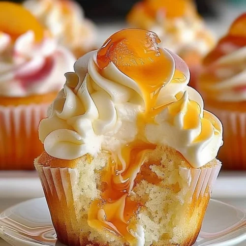 Delicious peach cupcakes topped with frosting and fresh peach slices.