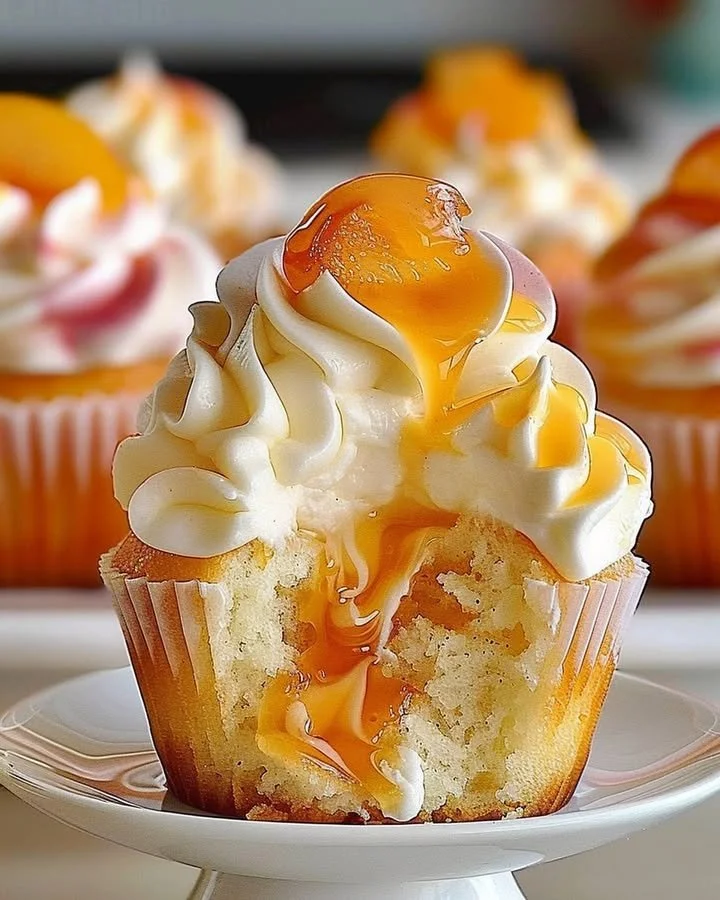 Delicious peach cupcakes topped with frosting and fresh peach slices.