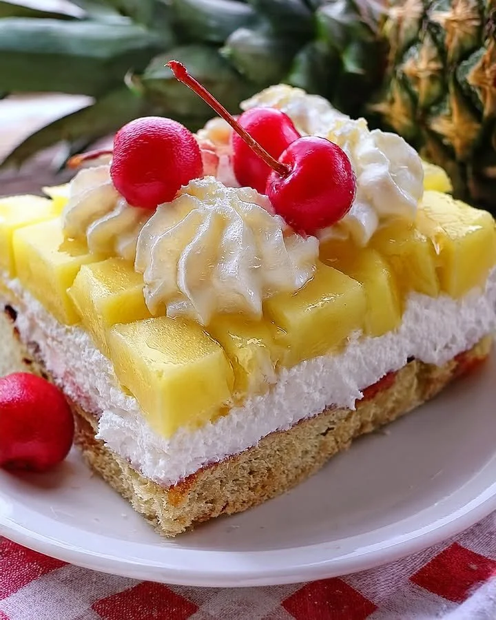 A slice of Pineapple Heaven Cake topped with whipped cream and pineapple slices.