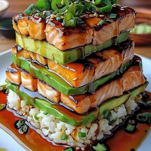 Teriyaki salmon avocado rice stack garnished with fresh ingredients
