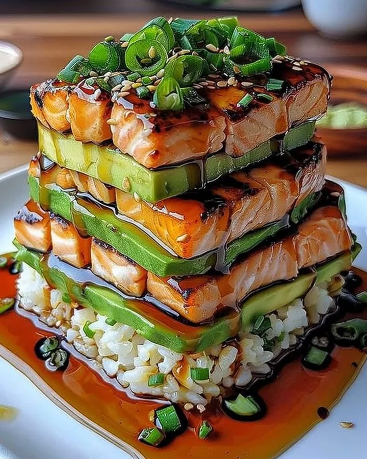 Teriyaki salmon avocado rice stack garnished with fresh ingredients