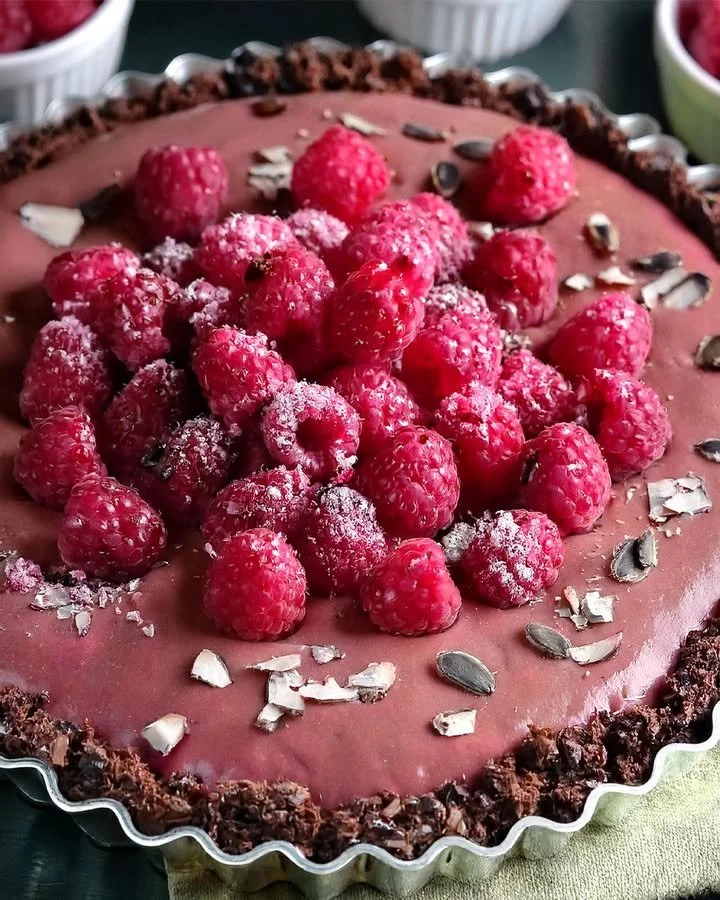 Delicious vegan raspberry chocolate tart with fresh raspberries on top