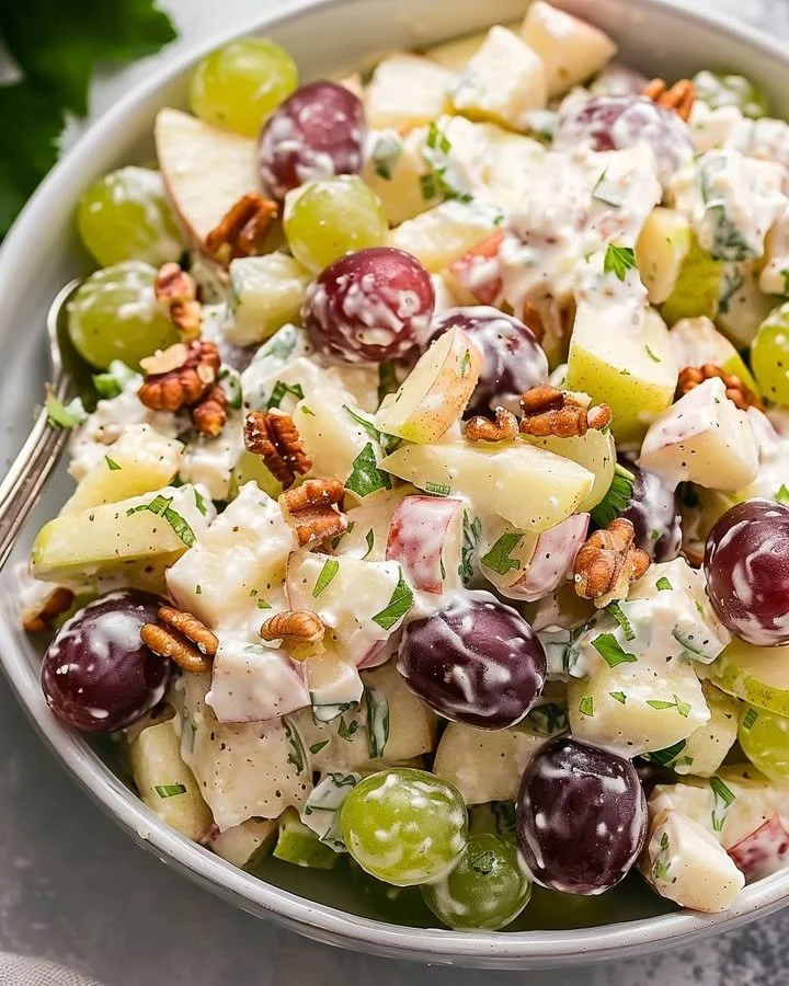 A vibrant bowl of Waldorf Salad featuring apples, walnuts, and grapes