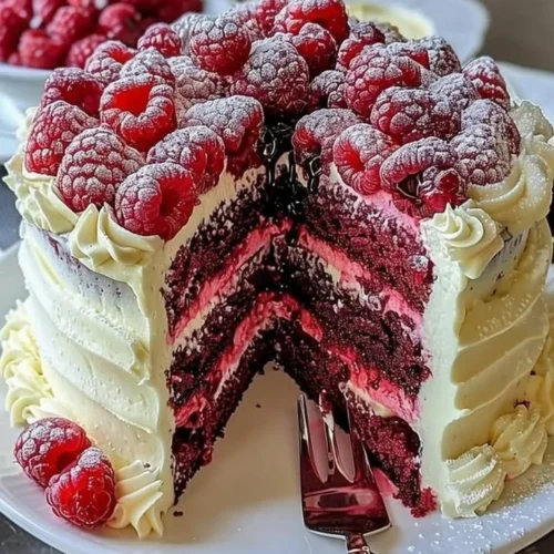 White Chocolate Raspberry Dream Cake topped with fresh raspberries and white chocolate shavings.